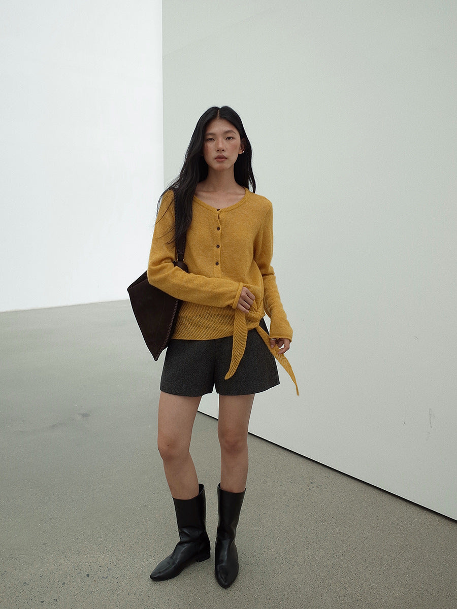 Woman wearing a mustard yellow Long Sleeve Knitted Mohair Wool Cardigan Sweater with Scarf and black shorts in an indoor setting
