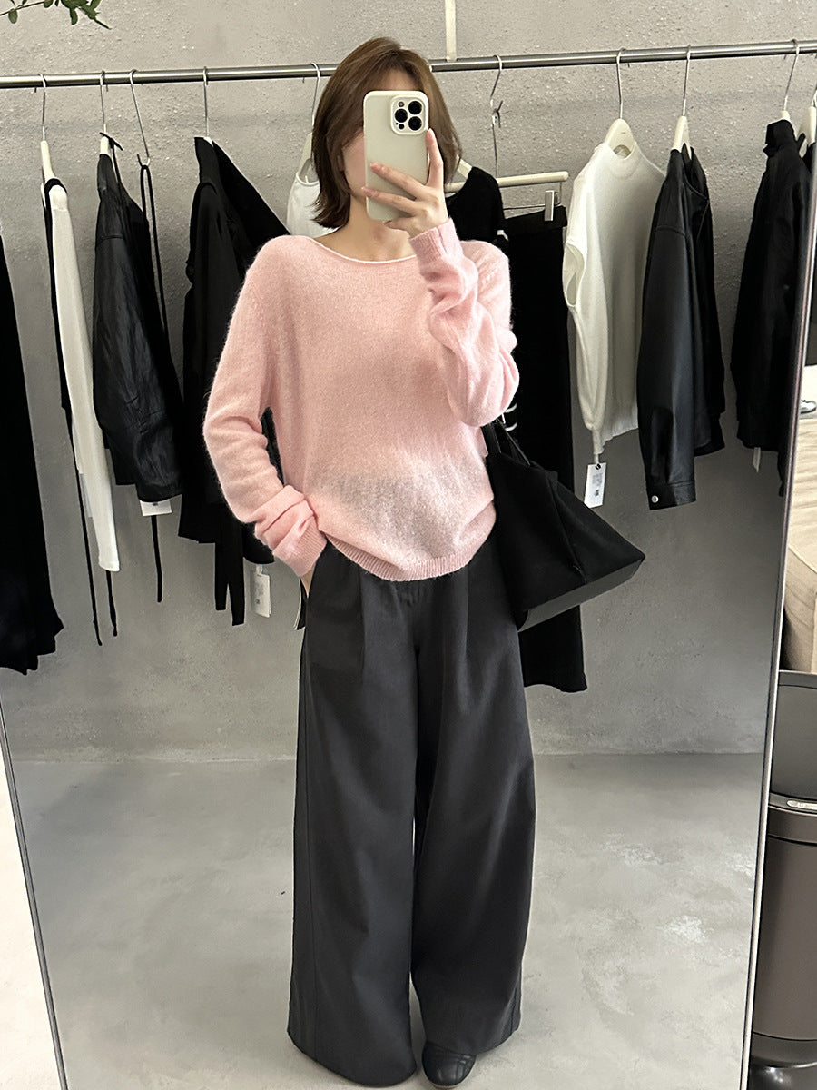 Person wearing a pink wool pullover sweater and black pants in a clothing fitting room.