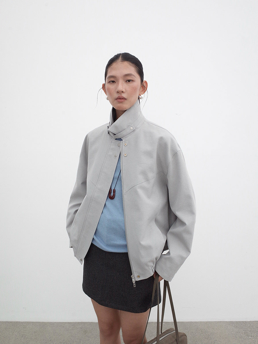 Person wearing a light gray Stand-up Collar jacket over a blue top and black skirt on a white background