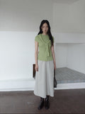 Woman wearing a green top and white Maxi Length A-Line Denim Skirt standing in a minimalistic room.