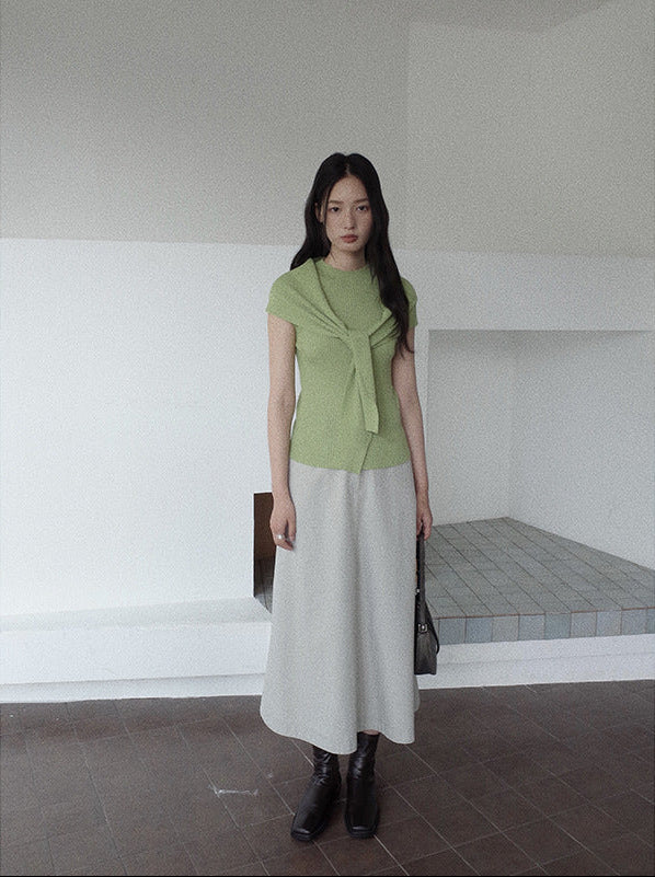 Woman wearing a green top and white Maxi Length A-Line Denim Skirt standing in a minimalistic room.