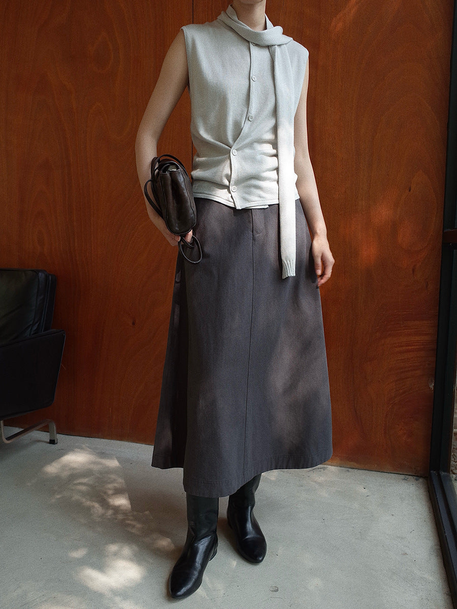 Person wearing a sleeveless top, long Maxi Length A-Line Denim Skirt, and holding a bag against a wooden wall.