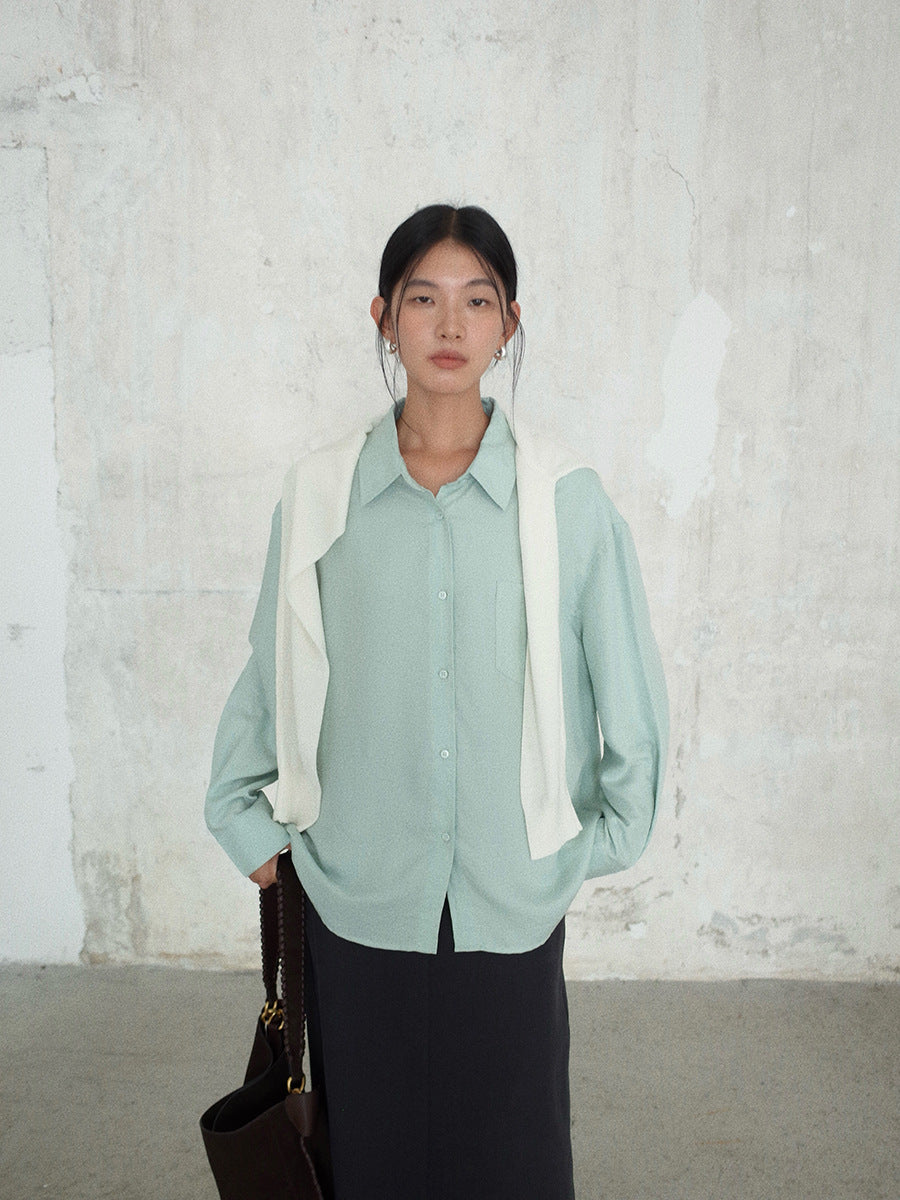 Woman wearing a light green Long-sleeved Relaxed Fit Shirt with a white panel against a textured white wall.