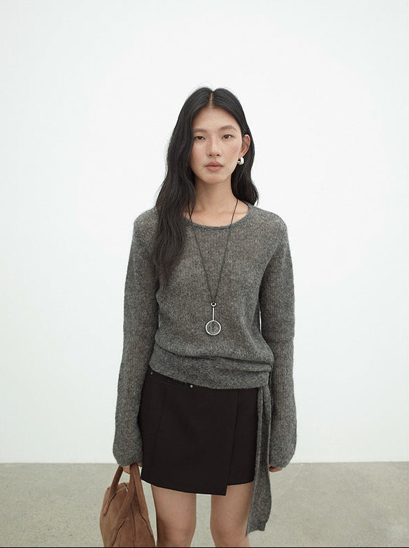 Woman wearing a gray Strap Waist Long-sleeved Mohair Wool Knitted Sweater and black skirt with a plain background