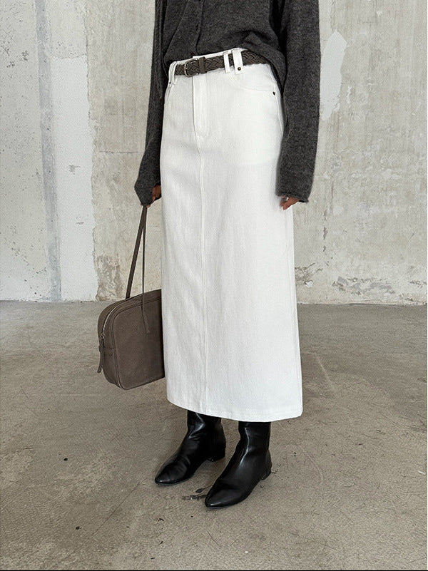 Person wearing a white High-waisted A-line Maxi Skirt, black boots, and holding a brown bag against a concrete wall.