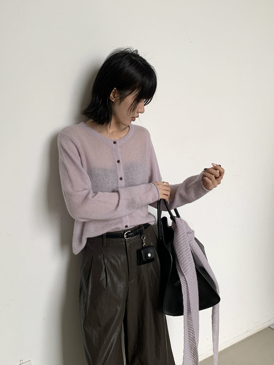 Woman in a light purple Long Sleeve Knitted Mohair Wool Cardigan Sweater with Scarf and dark pants holding a black handbag against a white wall.