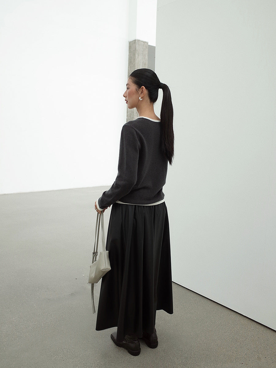 Woman in a Leather Drape Maxi A-Line Skirt outfit holding a white bag in a minimalistic setting