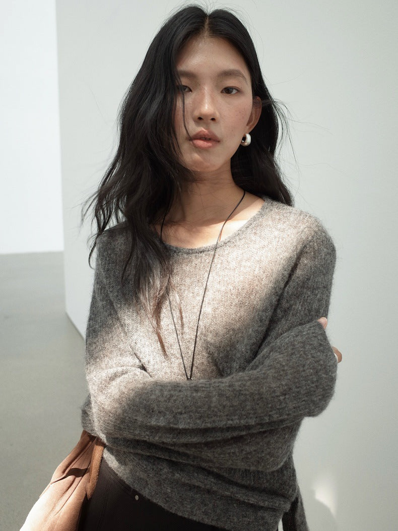 A woman wearing a fuzzy, light brown-gray crewneck Strap Waist Long-sleeved Mohair Wool Knitted Sweater with her arms crossed, standing in a minimalist white room.