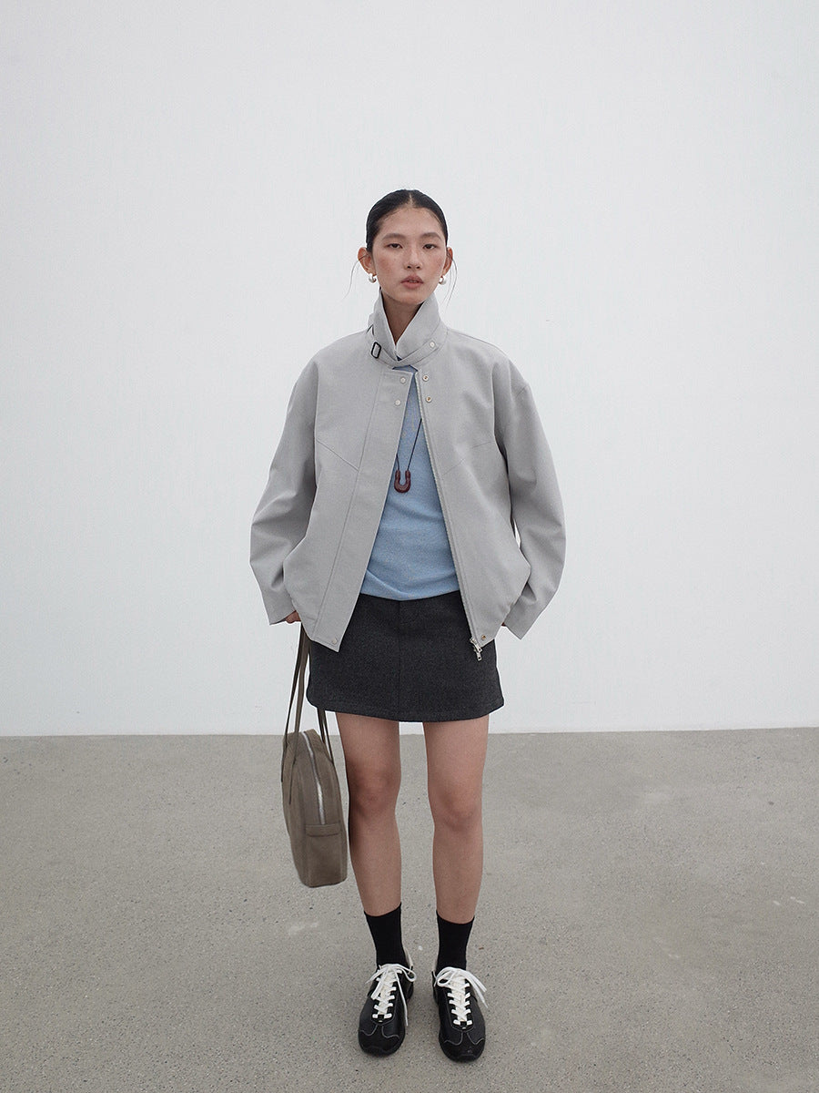 Person wearing a light gray Stand-up Collar Jacket , blue shirt, black skirt, and black shoes on a plain background