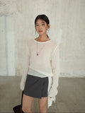 Woman wearing a light Strap Waist Long-sleeved Mohair Wool Knitted Sweater and dark skirt against a textured wall.