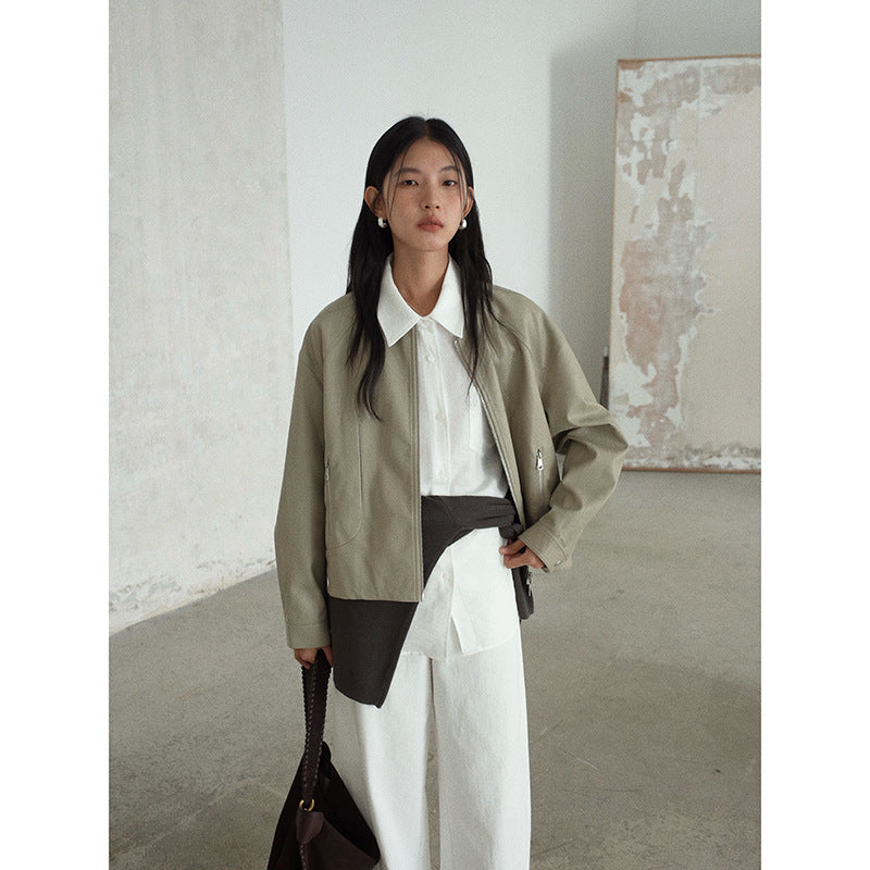 Woman wearing a beige jacket over a white Long-sleeved Relaxed Fit Shirt and dark pants in an indoor setting.