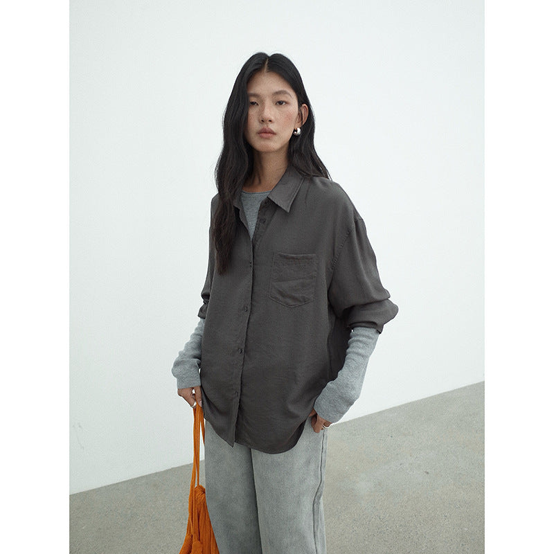 Woman wearing a gray oversized Long-sleeved Relaxed Fit Shirt and pants with an orange bag against a white background