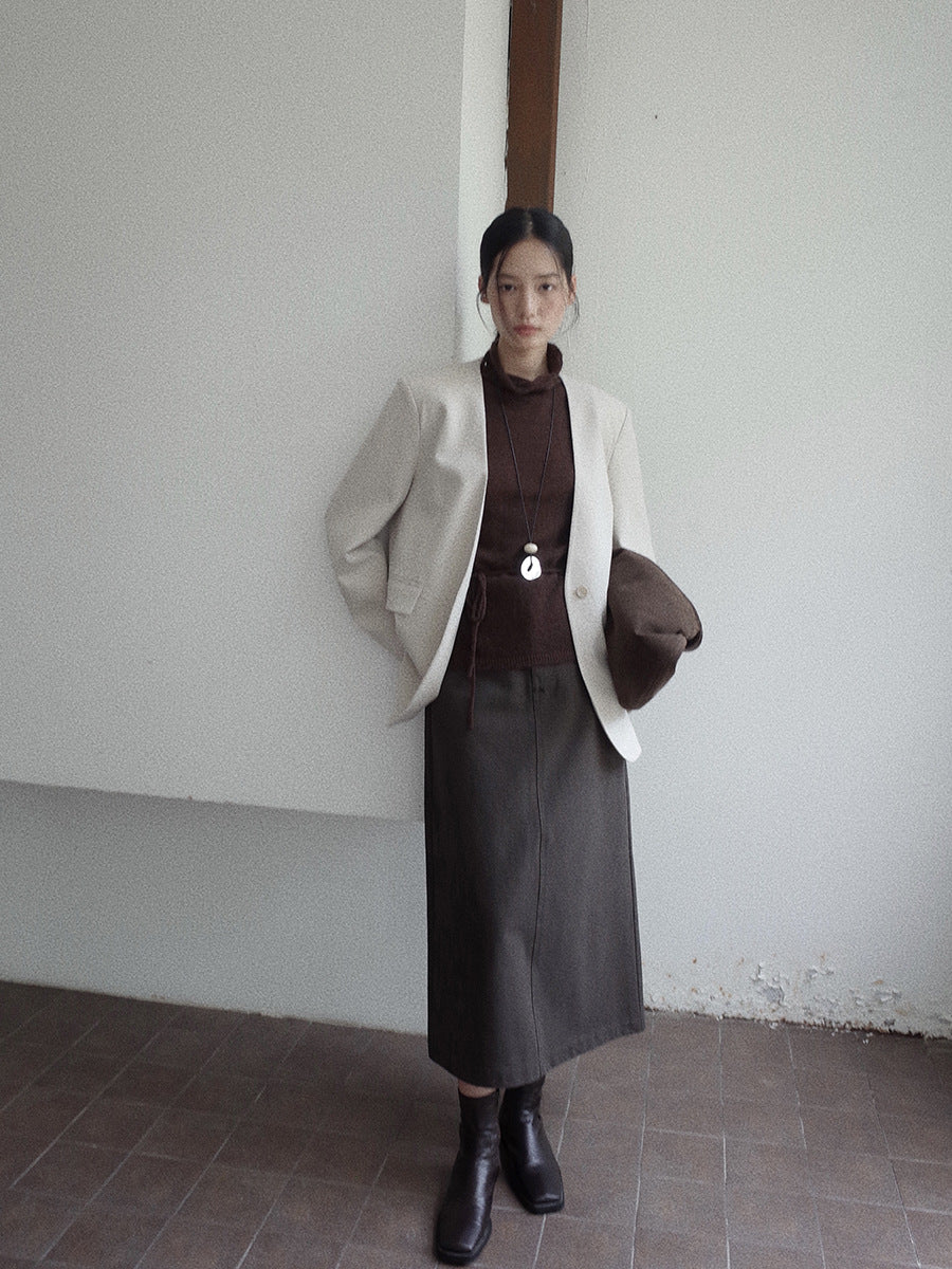 Person wearing a beige blazer, brown top, A-line Midi Denim Skirt, and black boots against a plain wall.