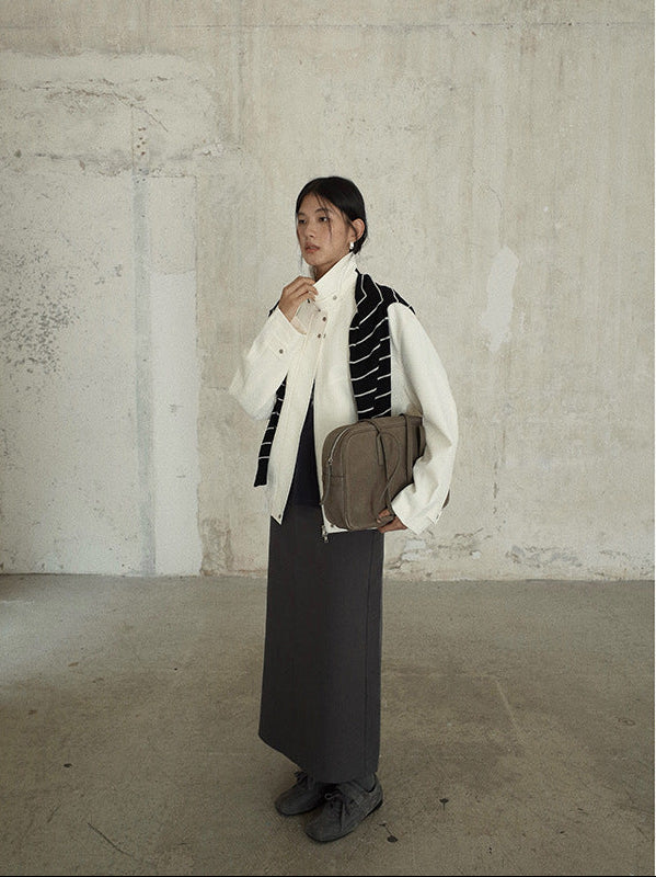 Person wearing a white Stand-up Collar Jacket  holding a bag against a plain wall