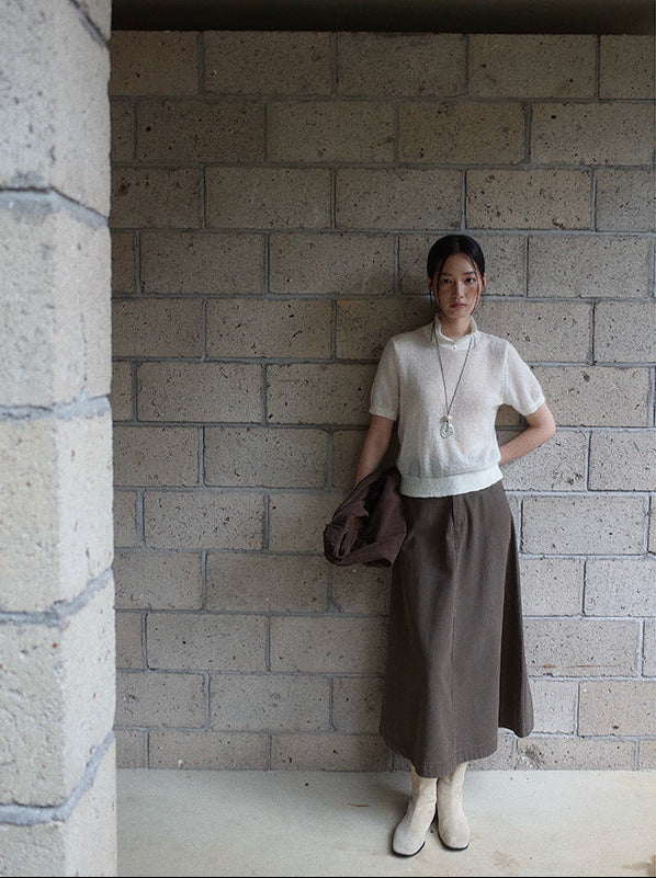 Person wearing a white top and brown Maxi Length A-Line Denim Skirt against a brick wall.