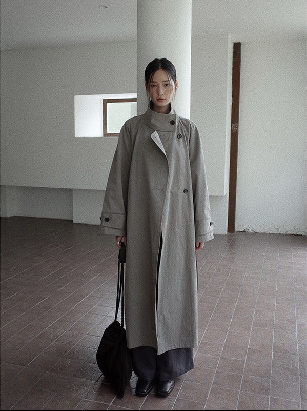Person wearing a long gray Stand-up Collar Long Trench Coat with Belt holding a black bag in an indoor setting.