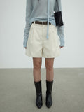Person wearing a light blue sweater, beige work dress Wide-leg shorts, and black boots against a plain background