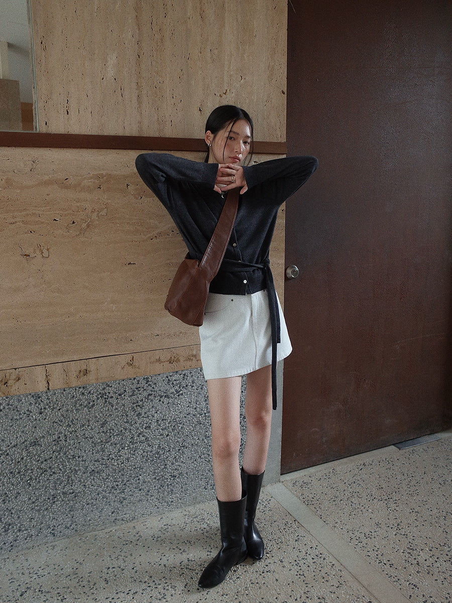 Woman posing in a cardigan and white Denim High-waisted Short Skirt outfit in a modern indoor setting