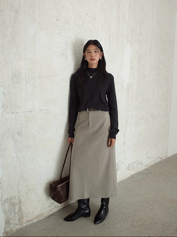 Woman wearing a black top and beige Smooth High-waisted A-line Maxi Skirt against a white wall
