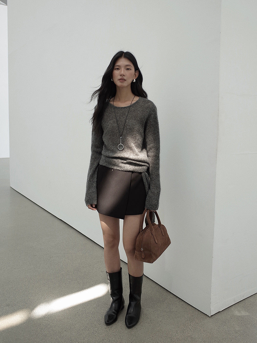 Woman wearing a gray Strap Waist Long-sleeved Mohair Wool Knitted Sweater, black leather skirt, and black boots in a minimalistic setting.