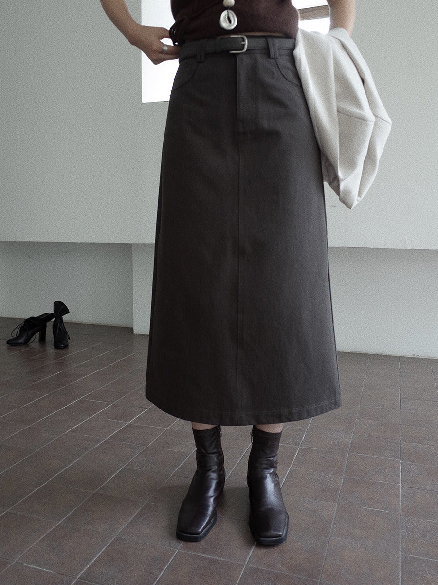 Person wearing a long dark grey A-line Midi Denim Skirt and black boots in an indoor setting.