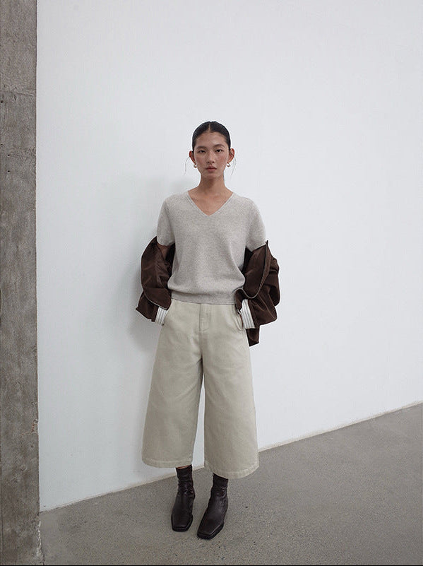 Person wearing a gray sweater and beige Cropped Wide-Leg Straight Jeans against a white wall.