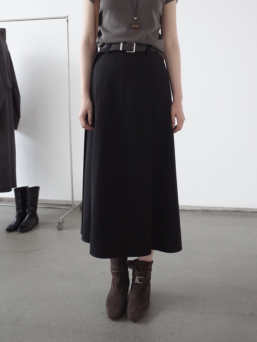Person wearing a black Maxi Length Drape A-Line Skirt and brown boots in a minimalistic setting