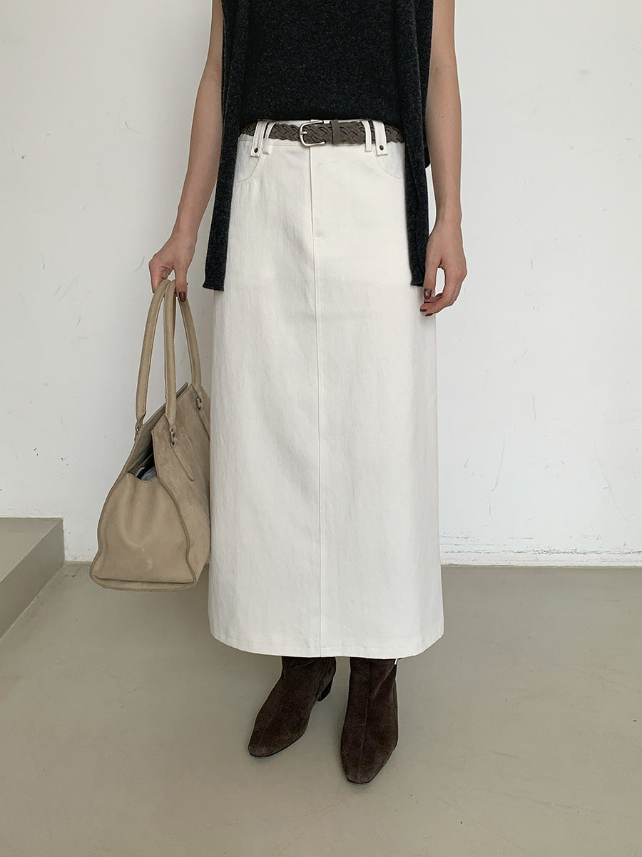 Woman wearing a white High-waisted A-line Maxi Skirt, black top, and brown boots holding a beige bag against a plain background.