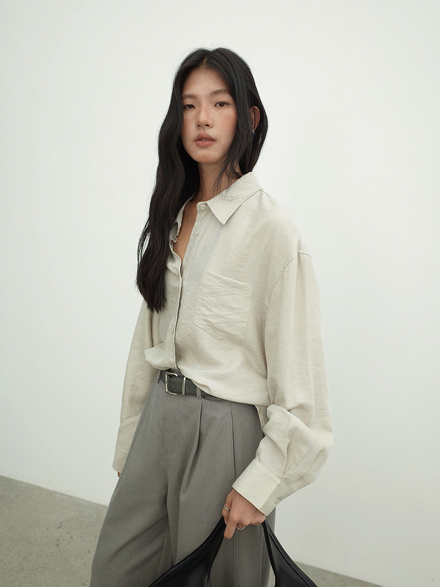 Woman wearing a light-colored Long-sleeved Relaxed Fit Shirt and gray pants against a white background