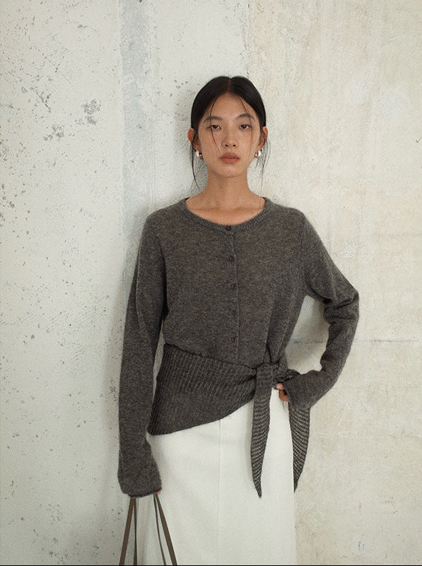 Woman wearing a gray Long Sleeve Knitted Mohair Wool Cardigan Sweater with Scarf with a tie detail against a textured wall.