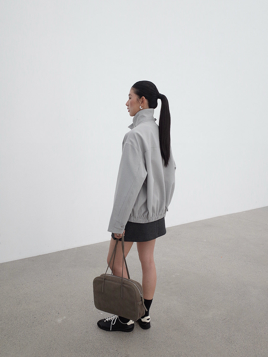 Person wearing a gray Stand-up Collar Jacket  holding a brown bag against a white background