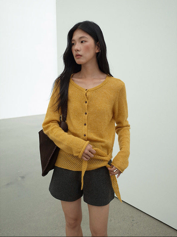 Woman wearing a mustard yellow Long Sleeve Knitted Mohair Wool Cardigan Sweater with Scarf and dark shorts against a plain background