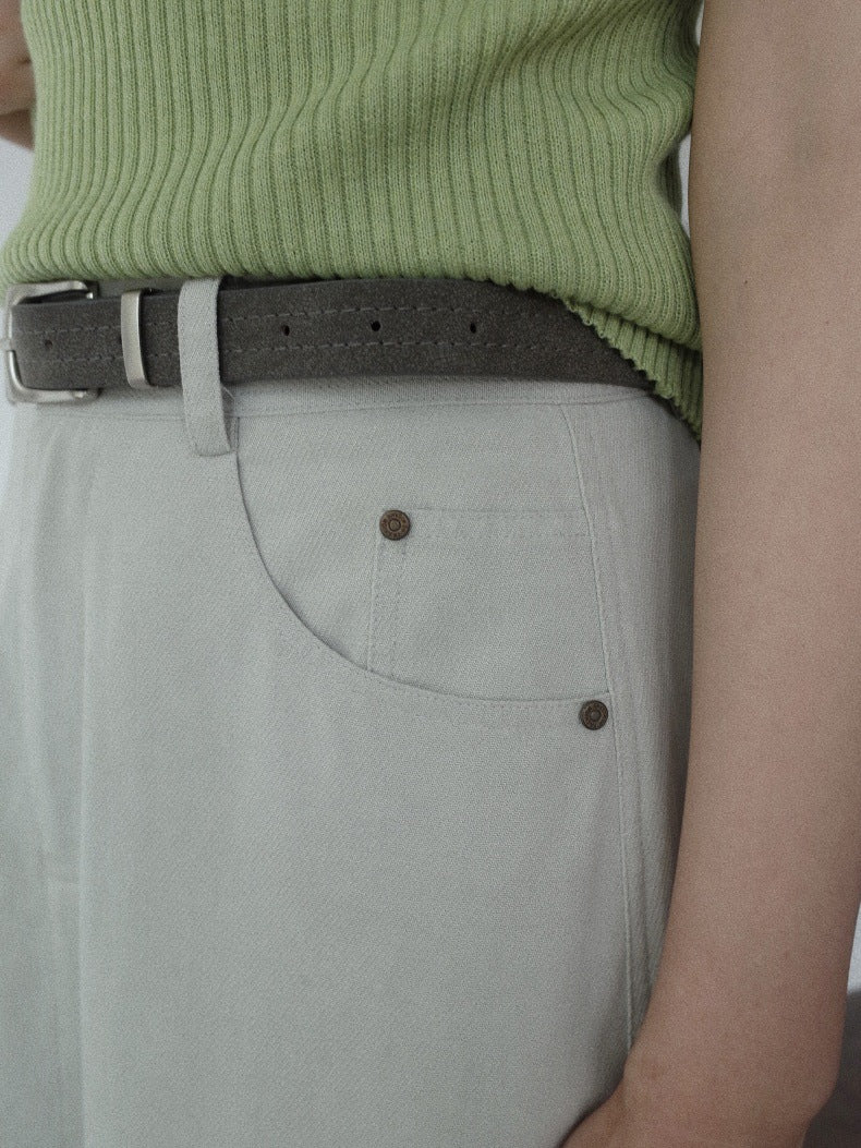 Close-up of a person wearing a light sage green ribbed knit top, a dark brown belt, and light gray Maxi Length A-Line Denim Skirt with a visible front pocket.