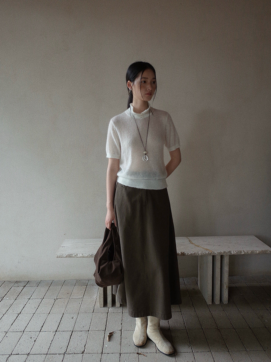 Woman in a white top and brown Maxi Length A-Line Denim Skirt standing in a minimalistic room.