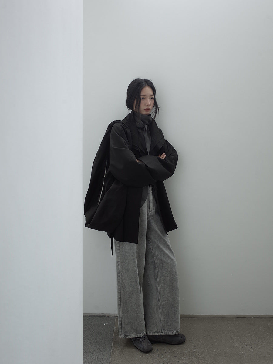 Person wearing a black Stand-up Collar Mid-Length Trench Coat and gray pants against a white wall