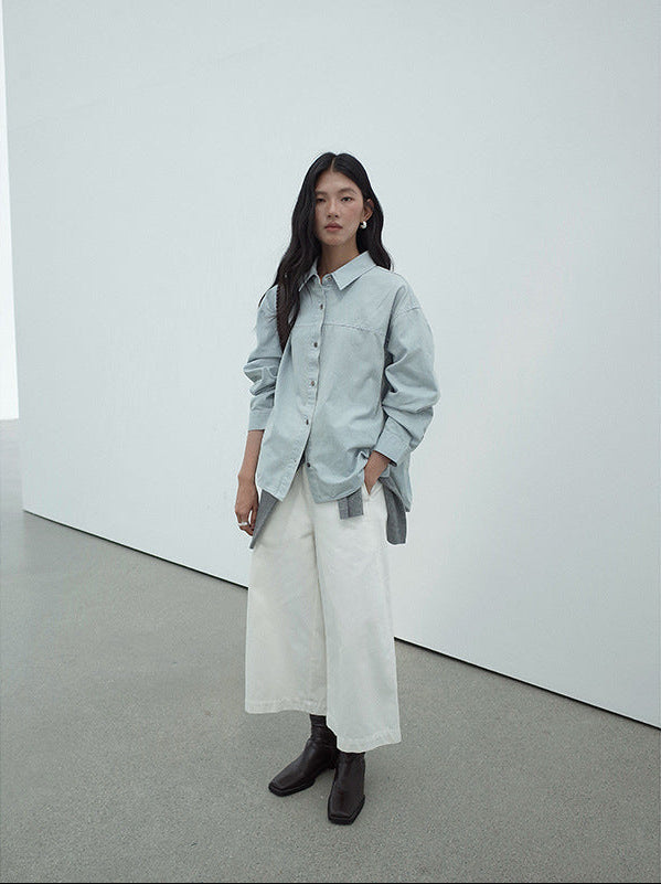 Woman wearing a light blue shirt, white Cropped Wide-Leg Straight Jeans, and dark shoes in a minimalistic setting.